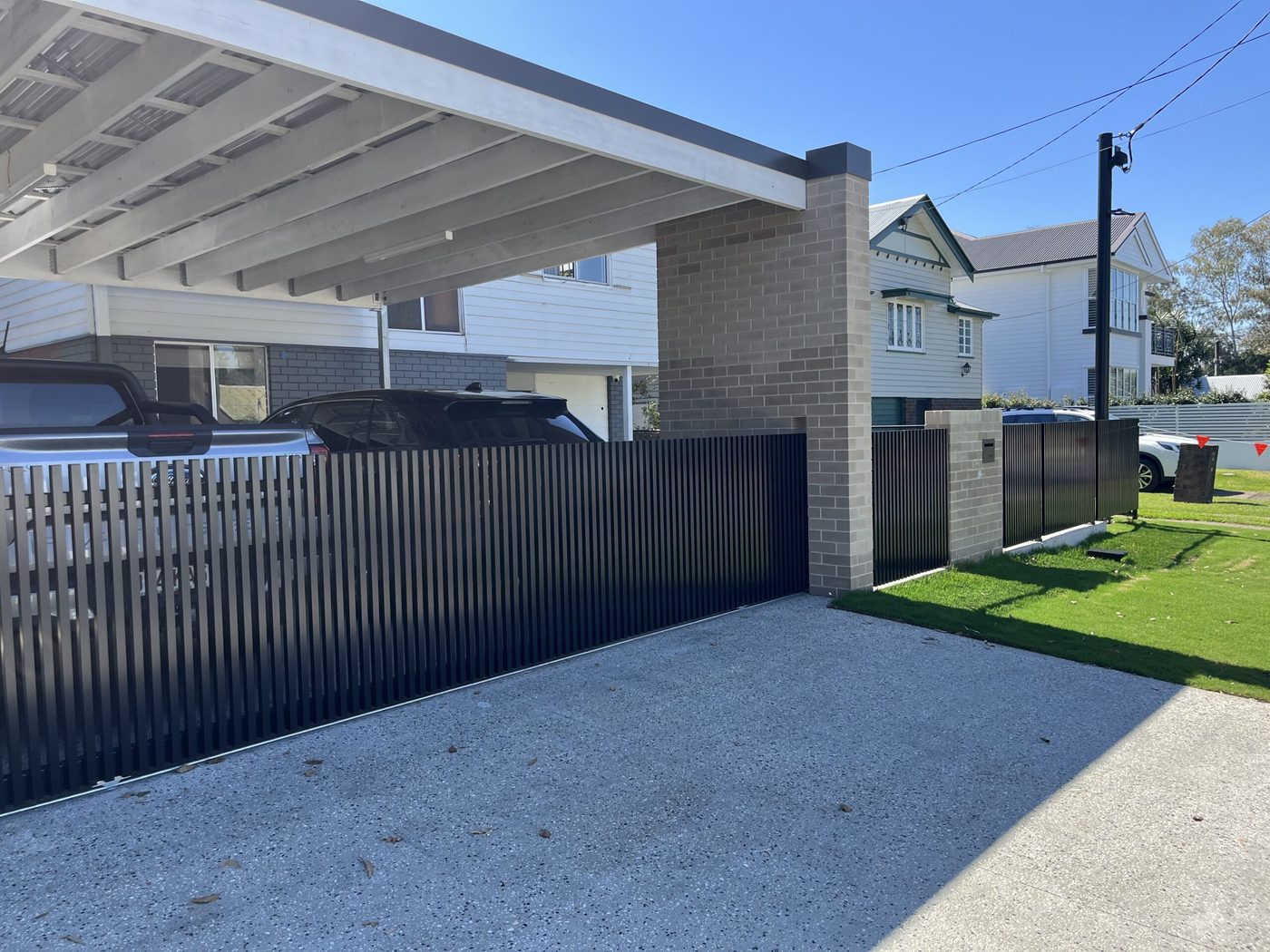 Vertical batten sliding gate beside a carport